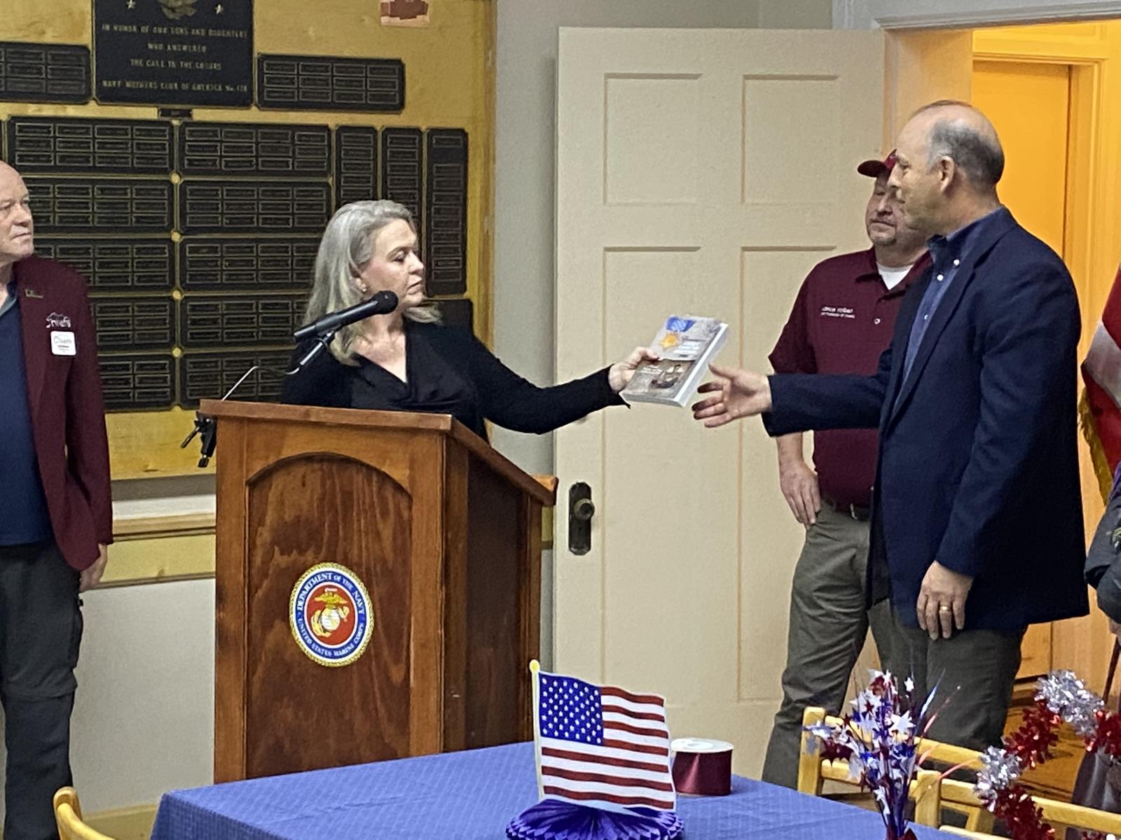 Farm Bureau Mutual Insurance Co. of Idaho CEO Todd Argall is presented a book about Pocatello Medal of Honor recipient James E. Johnson Nov. 11 during a Veterans Day celebration at the Bannock County Veterans Memorial Building.  